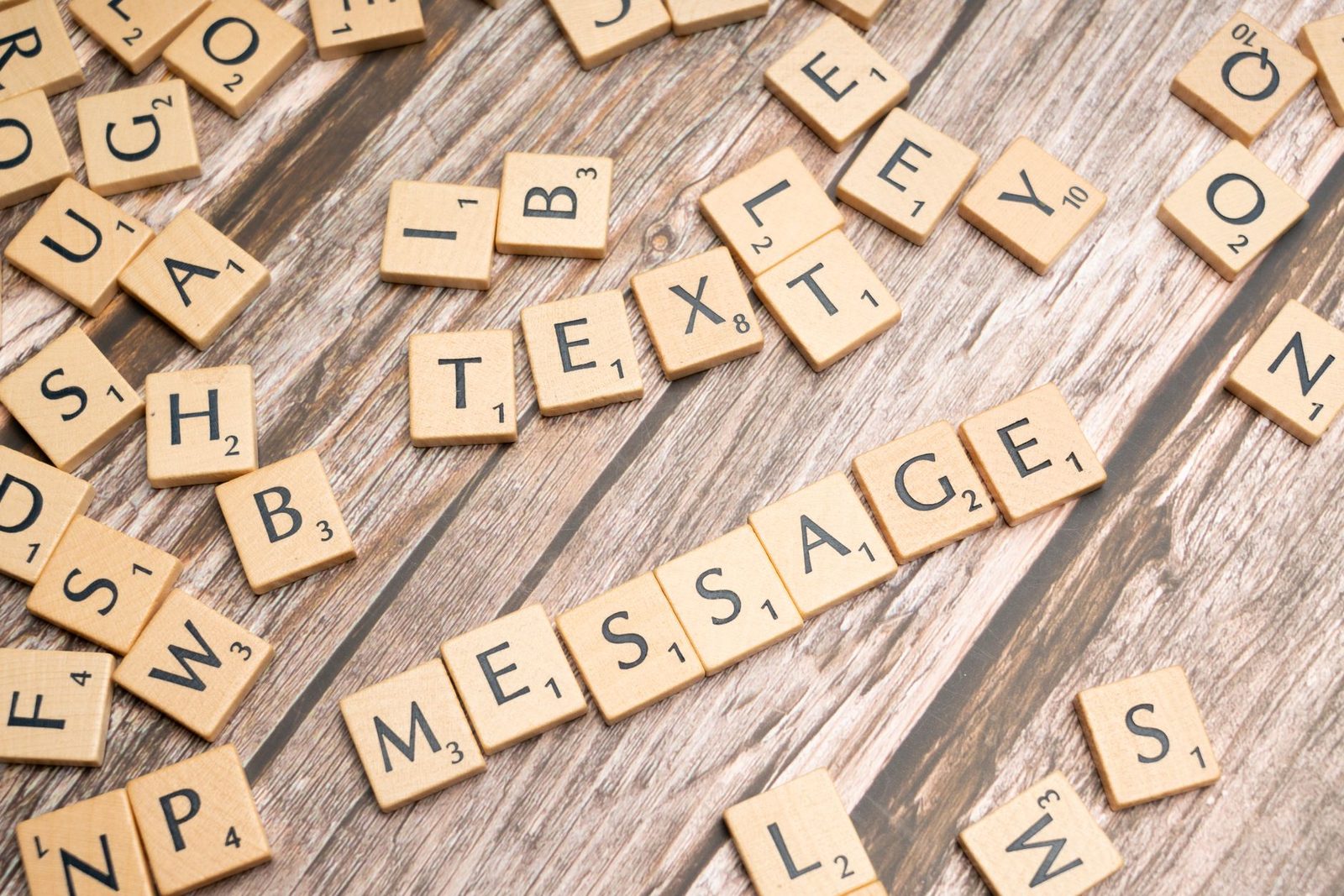 Tuiles de lettres formant les mots « text » et « message » sur une table en bois