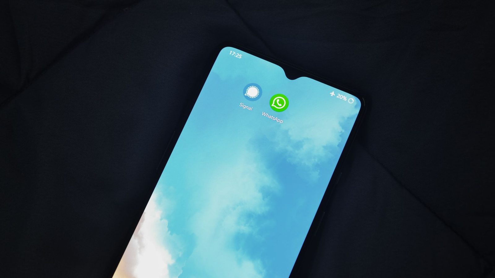 Smartphone appoggiato su un tessuto scuro, schermo acceso con le icone Signal e WhatsApp e la modalità aereo