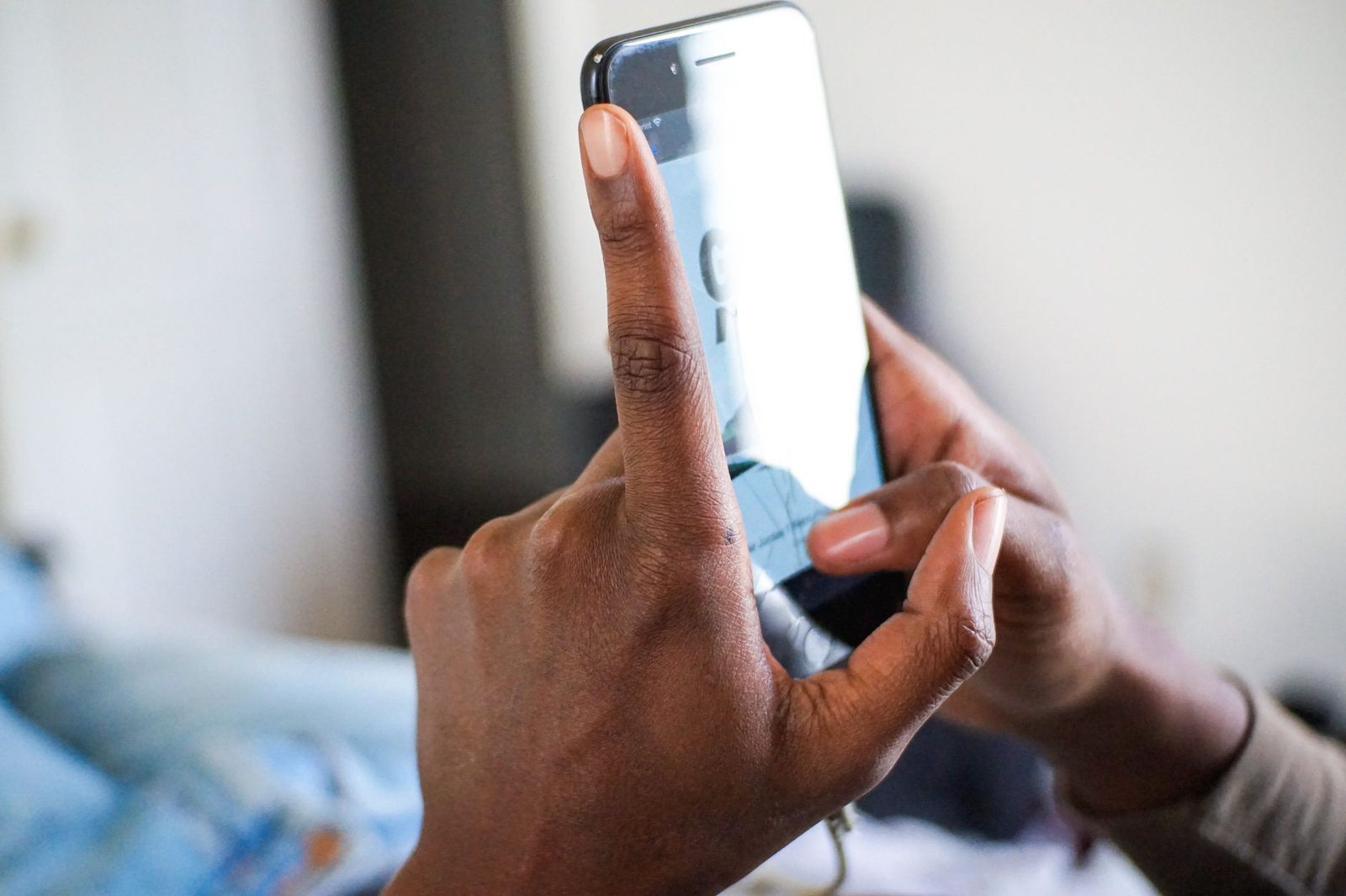 Nahaufnahme von Händen, die ein Smartphone halten und auf dem Bildschirm tippen, in einem Innenraum