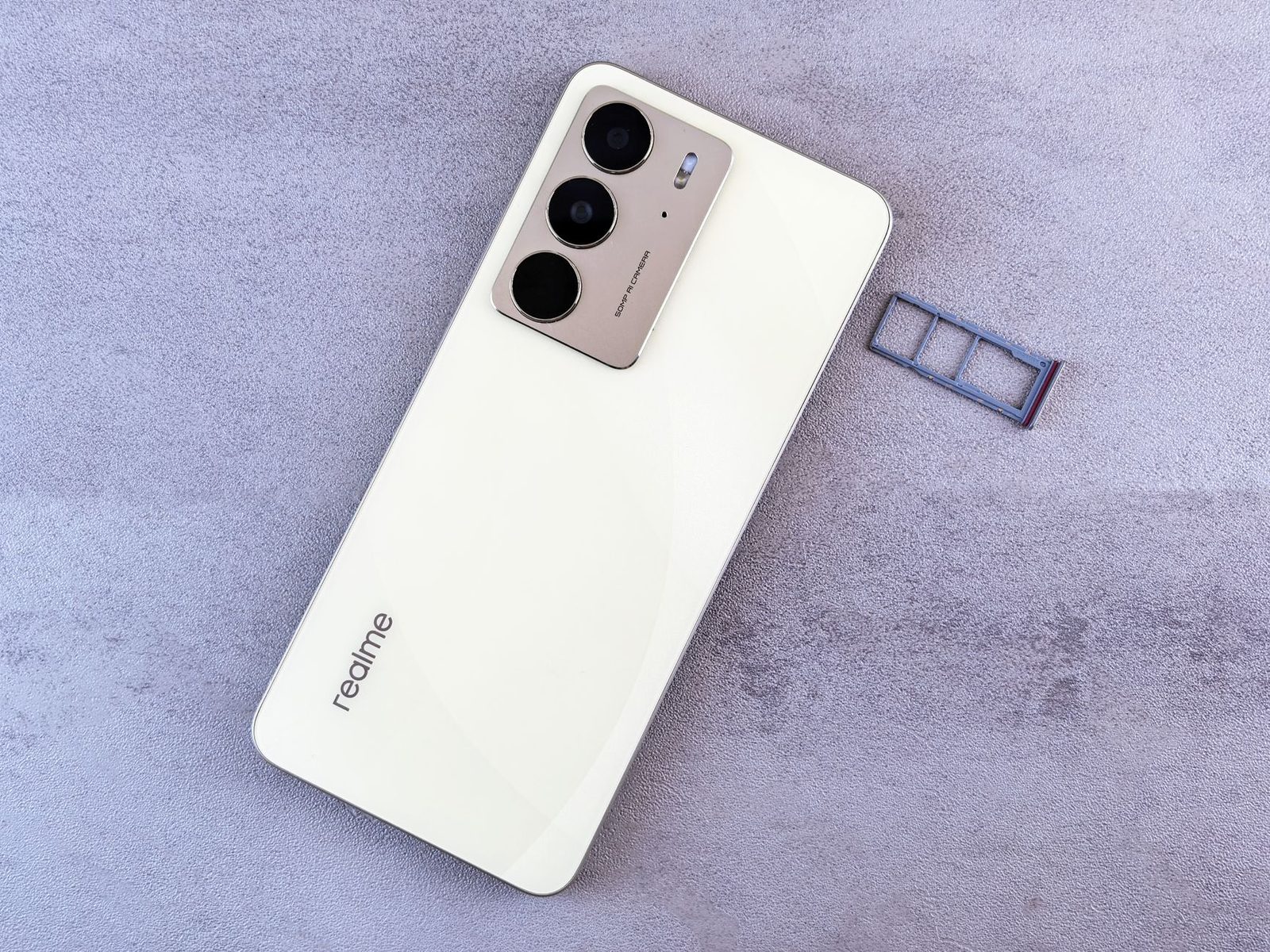White smartphone lying face down with its SIM card tray removed, on a light grey background