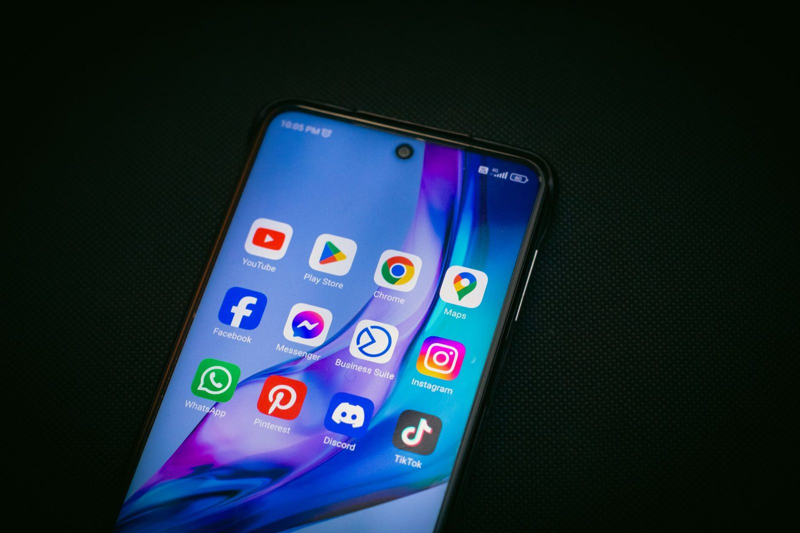 Smartphone posé sur fond noir affichant des applications et l'indicateur de réseau 4G en haut de l'écran