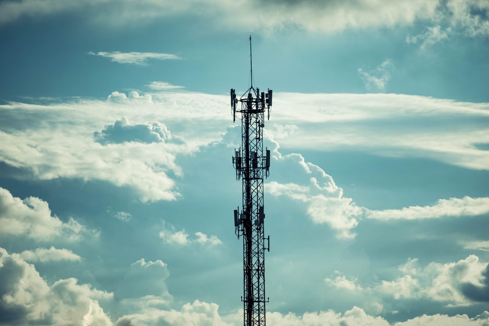 Zendmast voor mobiele telefonie met meerdere antennes, afgetekend tegen een bewolkte hemel
