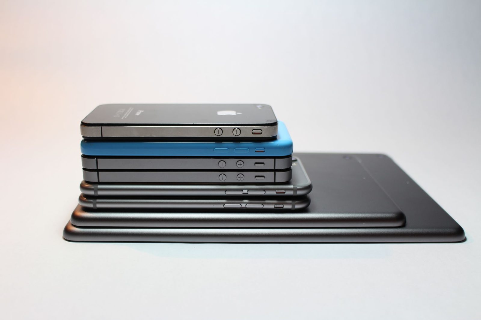 Pile de plusieurs smartphones empilés les uns sur les autres sur une tablette, fond clair