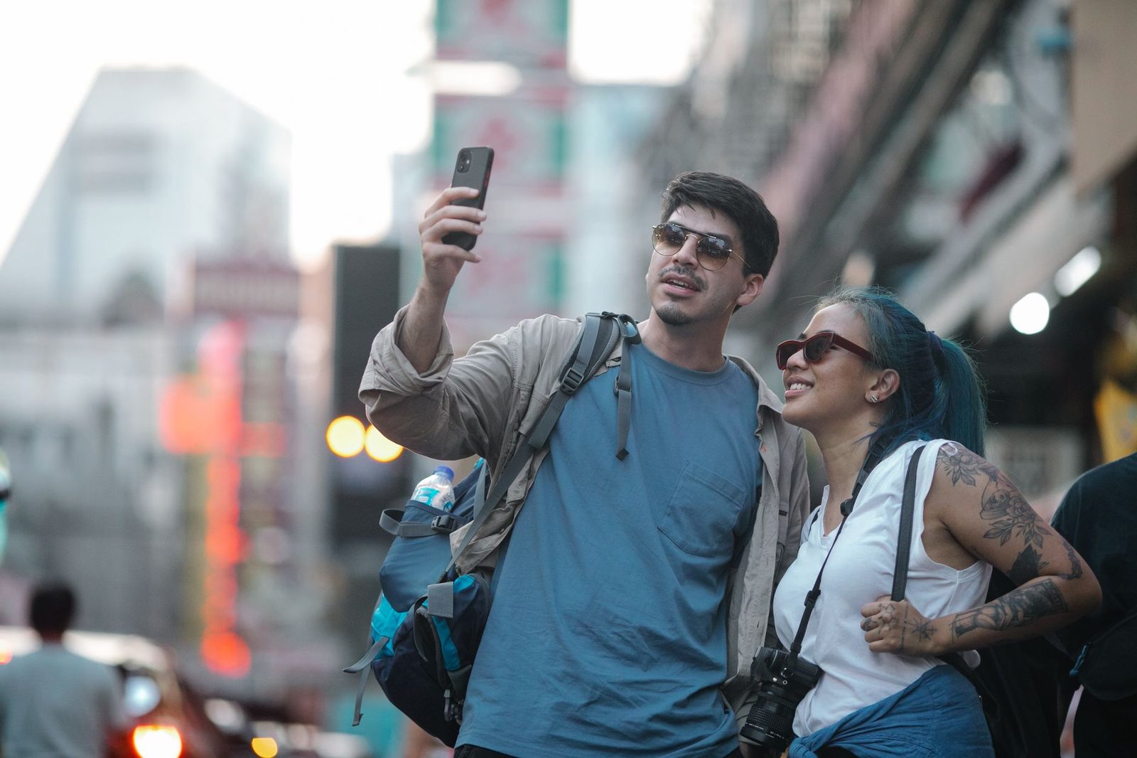 Couple of tourists taking a selfie with a smartphone on a busy street abroad